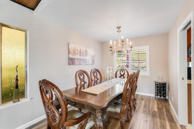 dining area with a chandelier, light wood-type flooring, and baseboards