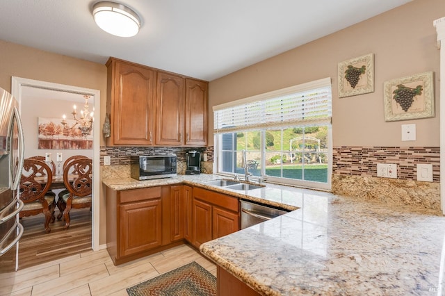 kitchen with appliances with stainless steel finishes, brown cabinetry, light stone counters, and tasteful backsplash