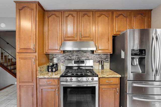 kitchen with tasteful backsplash, light stone counters, stainless steel appliances, and exhaust hood