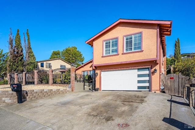 view of front of home featuring an attached garage, a gate, concrete driveway, and stucco siding