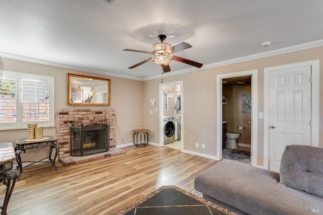 living room featuring a brick fireplace, crown molding, baseboards, and wood finished floors