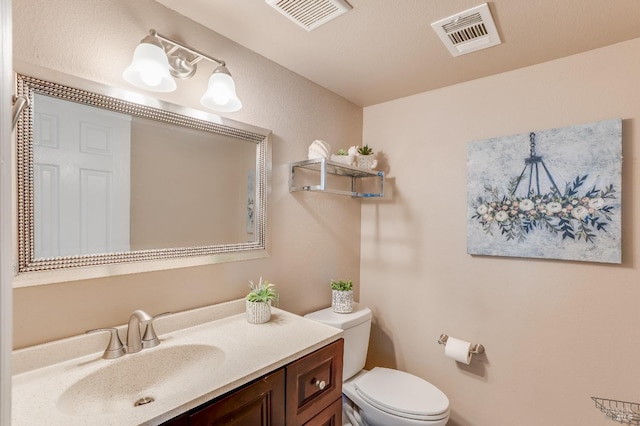 half bath featuring toilet, visible vents, and vanity