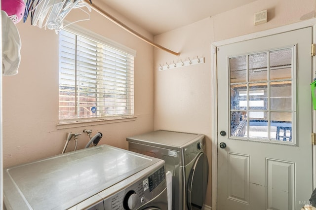 clothes washing area featuring laundry area, visible vents, and washer and clothes dryer