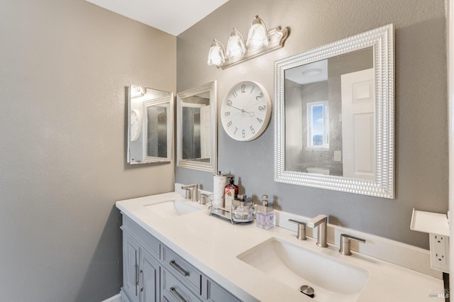 bathroom with double vanity, a sink, and a textured wall