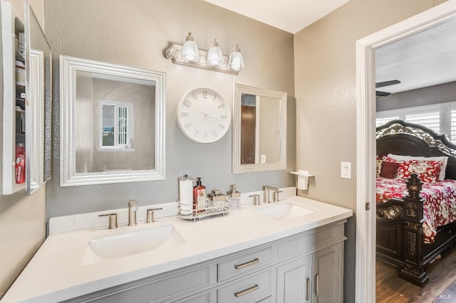 bathroom featuring double vanity, ensuite bath, a sink, and wood finished floors