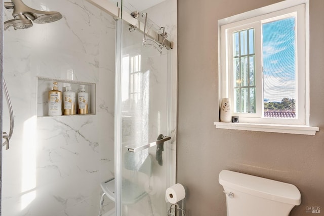 bathroom featuring toilet, plenty of natural light, and a marble finish shower