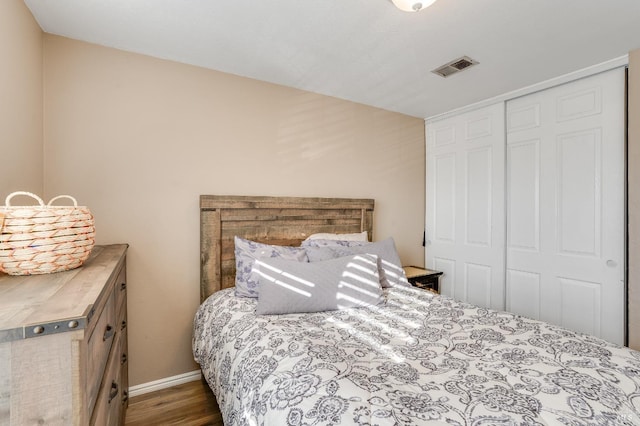 bedroom featuring a closet, wood finished floors, visible vents, and baseboards