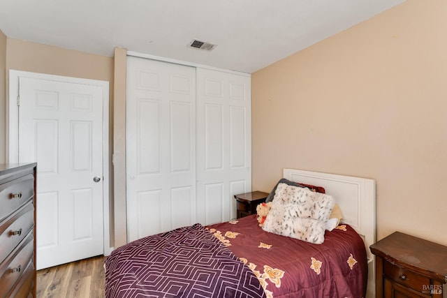 bedroom featuring a closet, visible vents, and wood finished floors