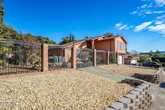 view of front of house featuring a fenced front yard, a gate, concrete driveway, and stucco siding