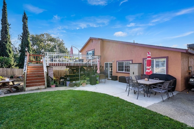 back of house with fence, stairway, a lawn, and stucco siding