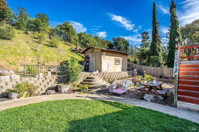 view of yard with stairs, fence, and an outdoor structure