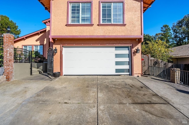 view of front of property with a garage, concrete driveway, fence, and stucco siding