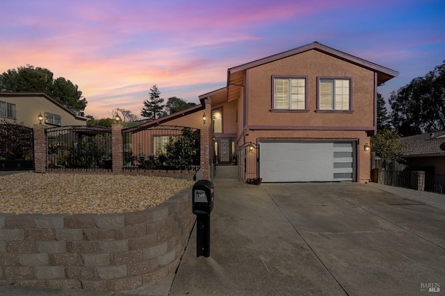 view of front of house with an attached garage, fence, driveway, a gate, and stucco siding