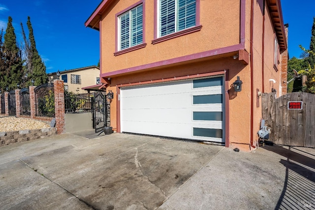 garage featuring driveway, a gate, and fence