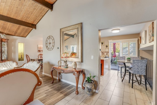 interior space featuring baseboards, wood ceiling, light wood-type flooring, high vaulted ceiling, and beam ceiling