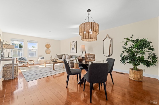 dining room featuring a chandelier, wood finished floors, visible vents, and baseboards