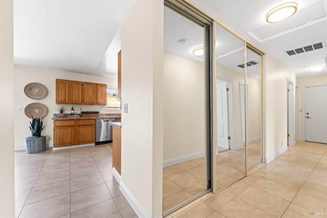 corridor featuring light tile patterned floors, baseboards, and visible vents