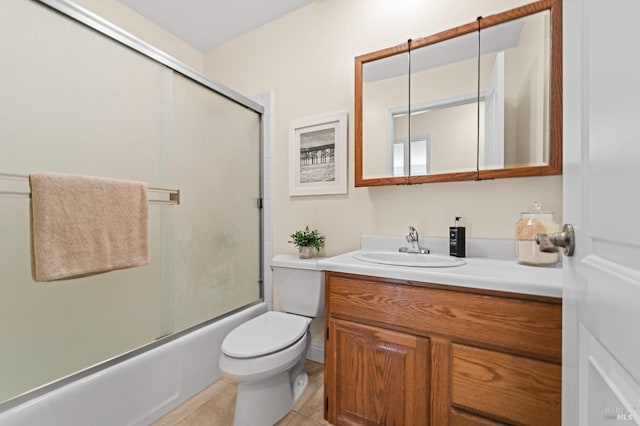 bathroom featuring tile patterned flooring, shower / bath combination with glass door, vanity, and toilet