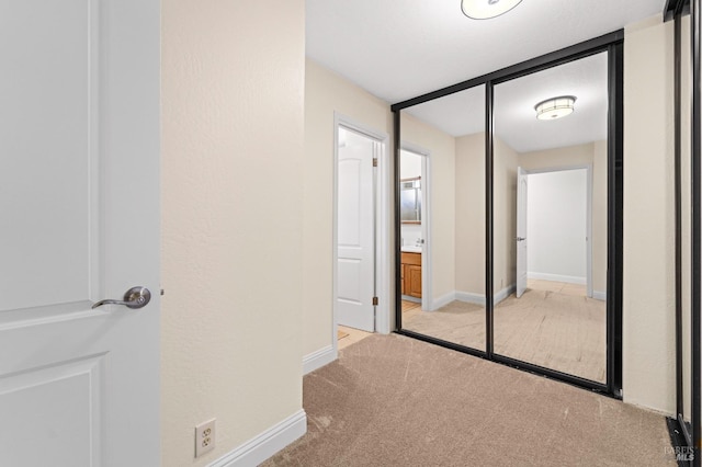 corridor featuring baseboards and light colored carpet