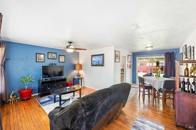 living room featuring baseboards, a ceiling fan, and hardwood / wood-style flooring