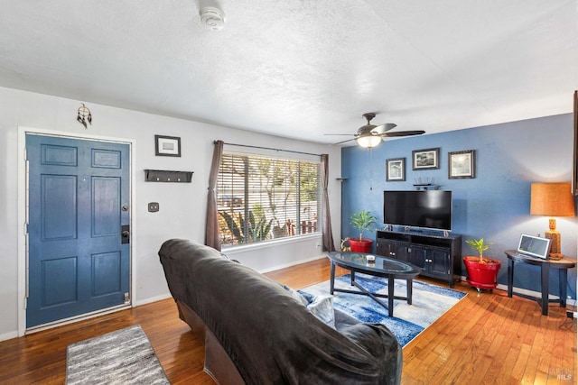 living area featuring baseboards, a textured ceiling, ceiling fan, and wood-type flooring
