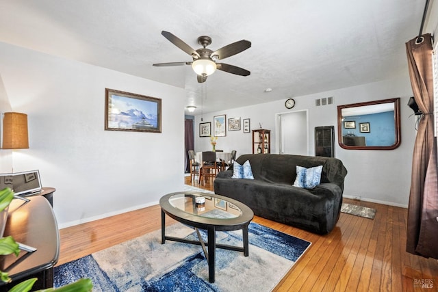 living area with hardwood / wood-style floors, a ceiling fan, baseboards, and visible vents