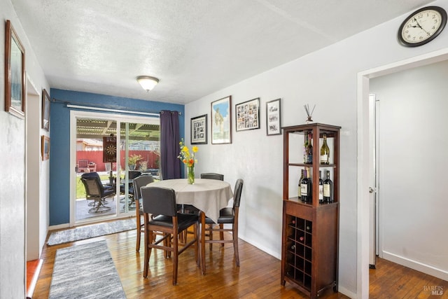 dining space with a textured ceiling, baseboards, and wood-type flooring