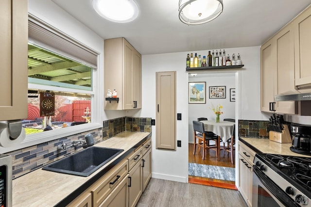 kitchen with light wood-type flooring, backsplash, light countertops, and a sink