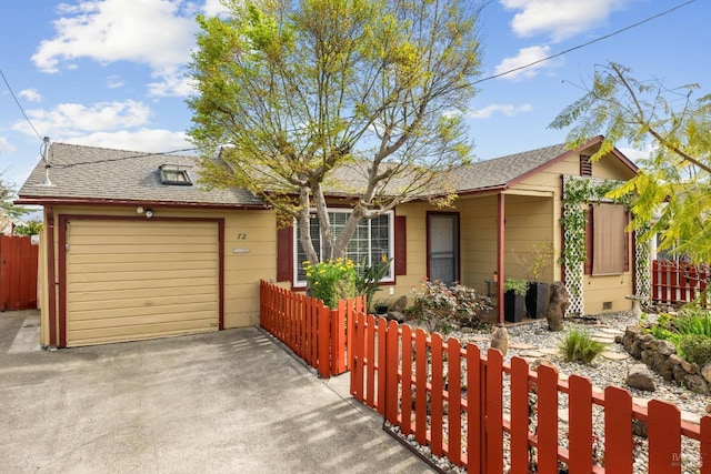 ranch-style house with a shingled roof, a fenced front yard, concrete driveway, and a garage