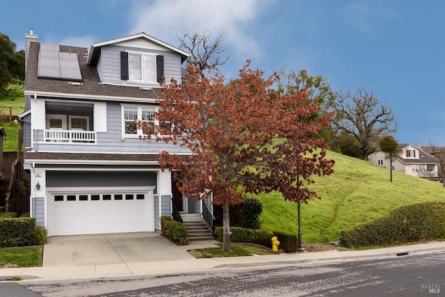 view of front of property featuring a chimney, solar panels, an attached garage, a front yard, and a balcony