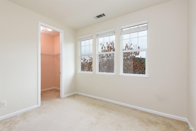 spare room with baseboards, visible vents, and light colored carpet