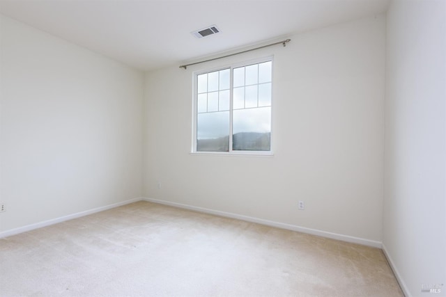 unfurnished room with light carpet, visible vents, and baseboards