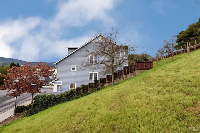 view of side of property featuring stairs, a mountain view, and a lawn