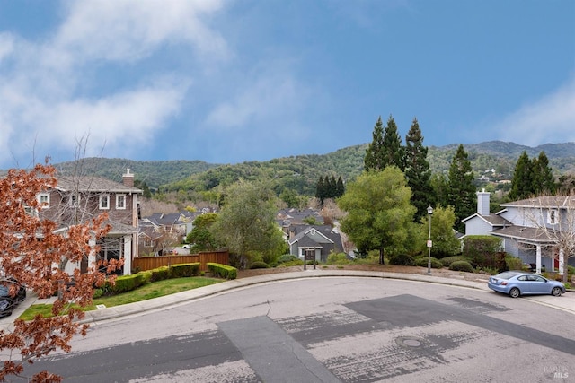 view of street featuring a residential view, a mountain view, street lights, and curbs