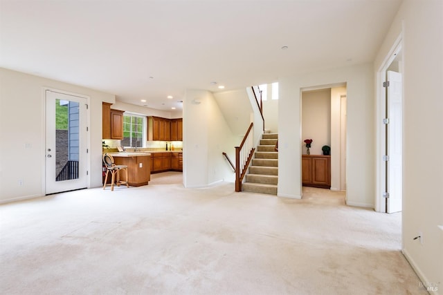 unfurnished living room featuring baseboards, stairway, light colored carpet, and recessed lighting