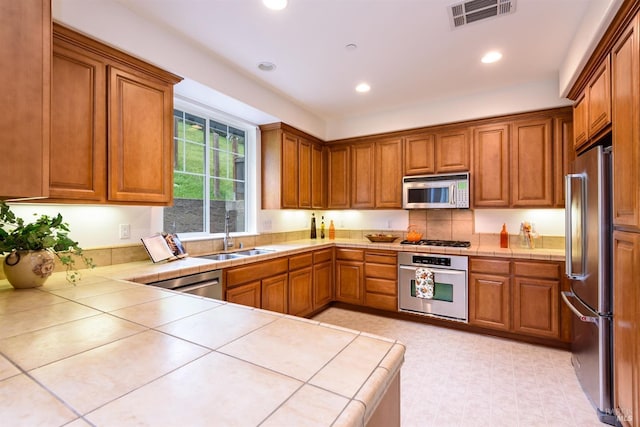 kitchen with stainless steel appliances, brown cabinets, visible vents, and a sink