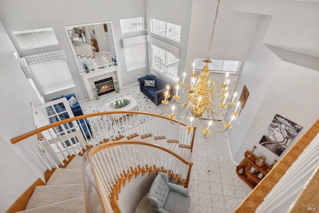 stairway with tile patterned floors, a high ceiling, baseboards, and a high end fireplace