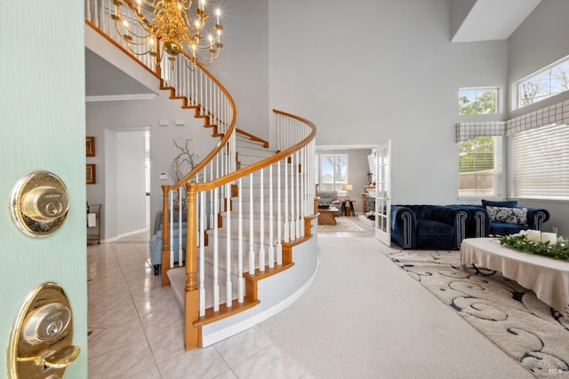 stairway featuring a chandelier, a wealth of natural light, a towering ceiling, and tile patterned floors