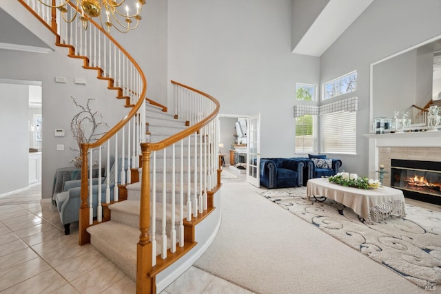 stairs with a tile fireplace, an inviting chandelier, carpet, a high ceiling, and tile patterned flooring