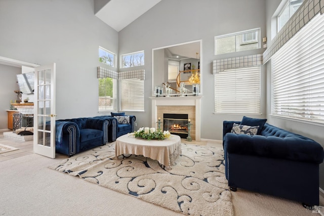 living room with baseboards, carpet, french doors, a fireplace, and high vaulted ceiling