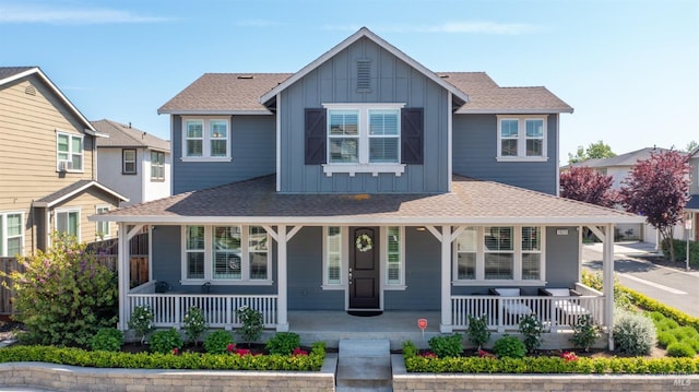 view of front facade featuring covered porch, board and batten siding, and roof with shingles