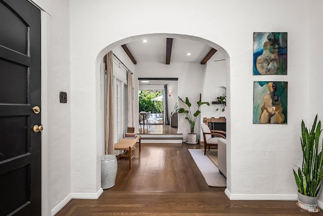 entryway with dark wood-style floors, arched walkways, beam ceiling, and baseboards