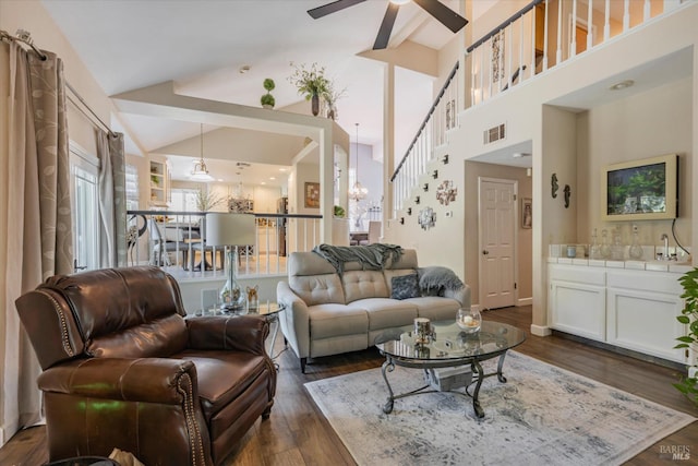 living room with visible vents, dark wood finished floors, stairway, vaulted ceiling, and ceiling fan with notable chandelier