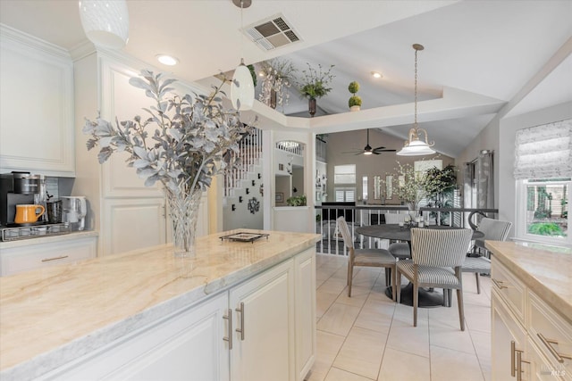 kitchen with lofted ceiling, light tile patterned floors, visible vents, light stone countertops, and pendant lighting