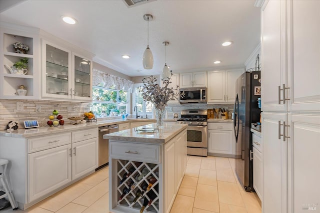 kitchen with stainless steel appliances, a center island, white cabinets, and pendant lighting