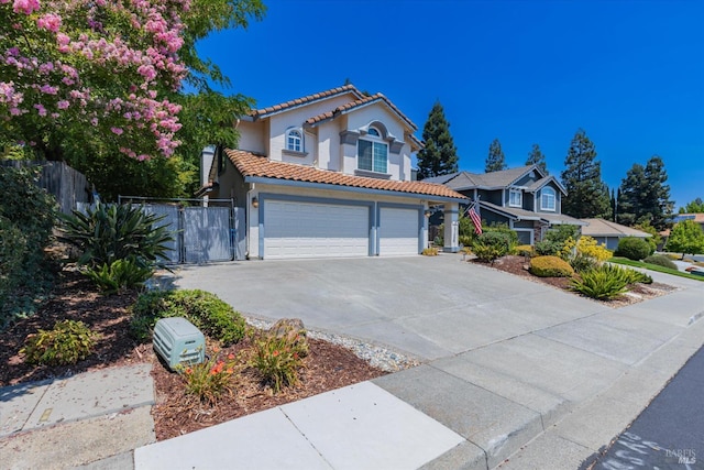 mediterranean / spanish-style house featuring driveway, an attached garage, a tile roof, and fence