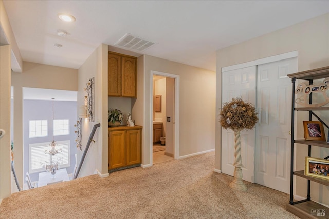 hallway with a notable chandelier, light colored carpet, an upstairs landing, baseboards, and visible vents