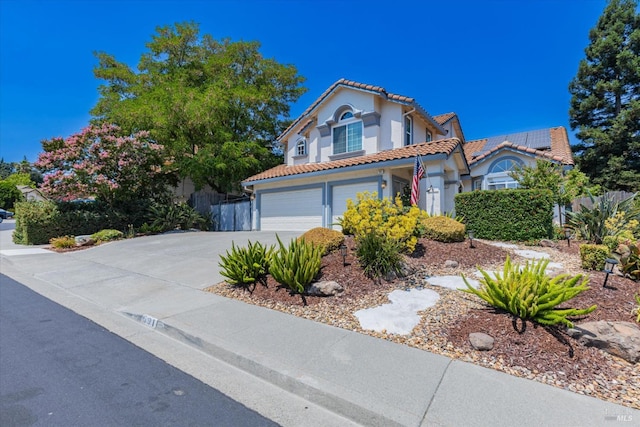 mediterranean / spanish-style home featuring a tile roof, stucco siding, roof mounted solar panels, a garage, and driveway