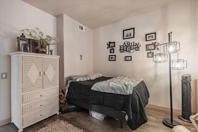 bedroom featuring visible vents, baseboards, and wood finished floors