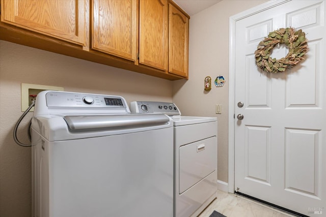 clothes washing area with cabinet space, baseboards, and independent washer and dryer